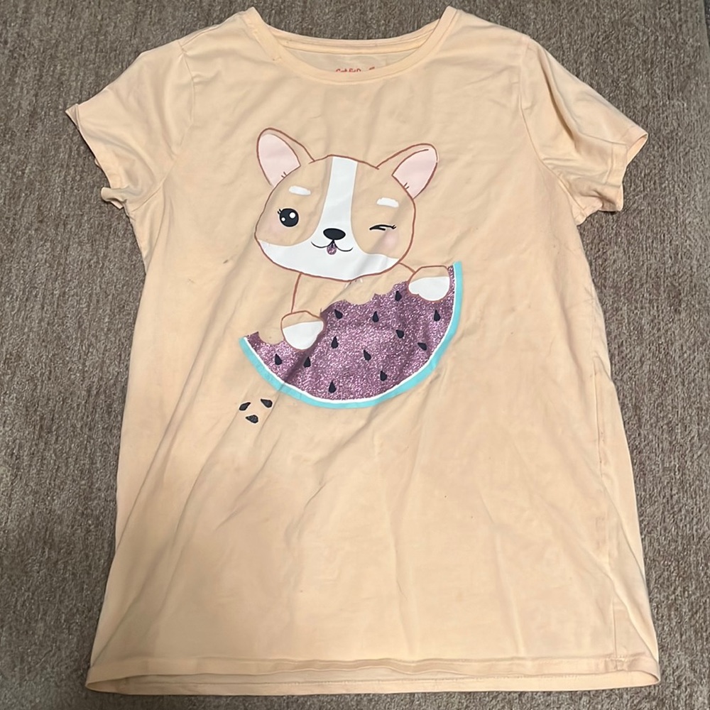 This is a kids shirt with a dog holding a watermelon